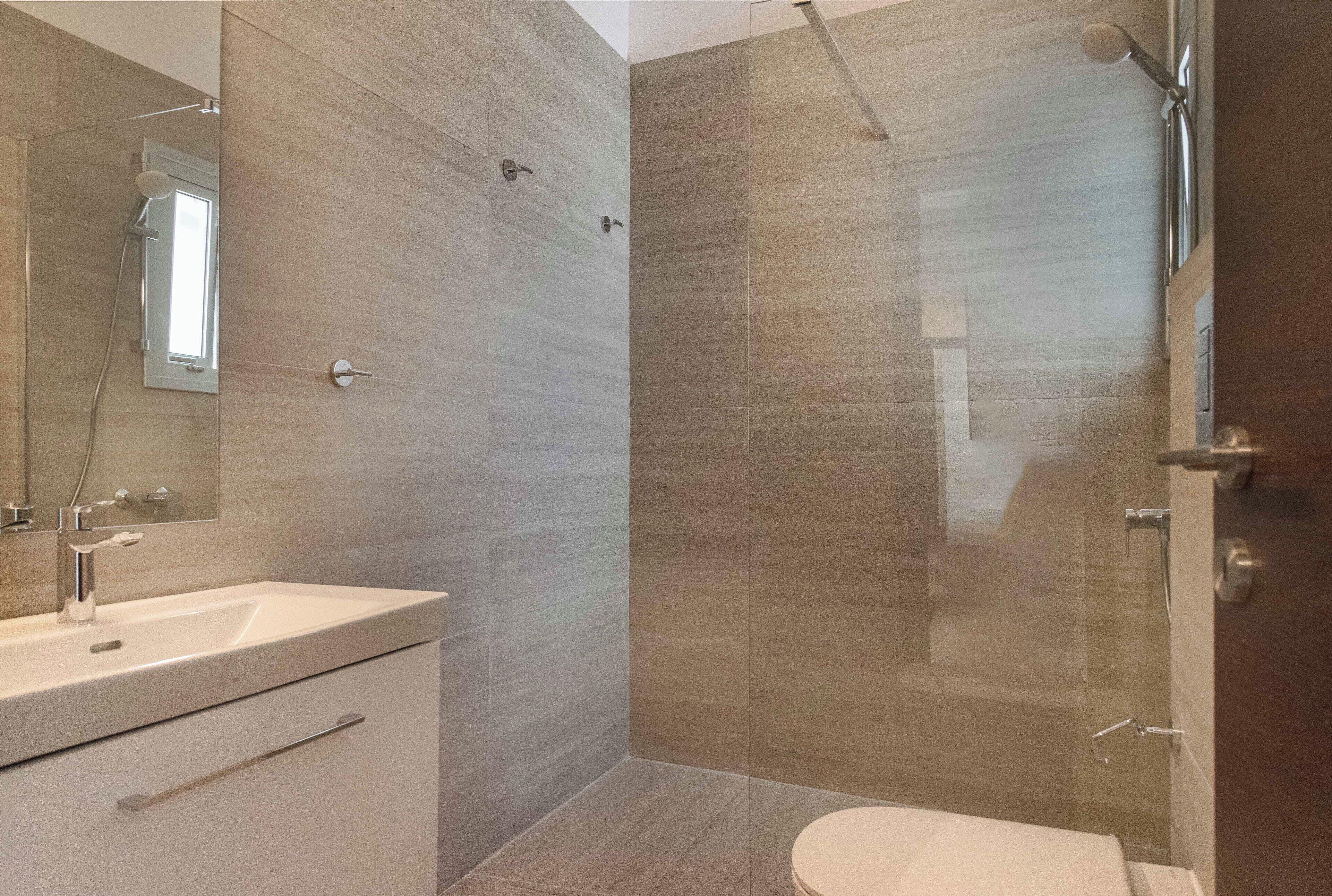 Une salle de bain moderne avec une douche à parois de verre, un lavabo et des toilettes.