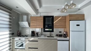 A modern kitchen with a built-in oven, a refrigerator, and a window above the sink.