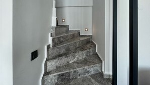 A staircase with marble steps and a modern design, leading to a landing with a small window.