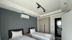 A hotel room with two beds, a wardrobe, a bathroom, and a ceiling light.