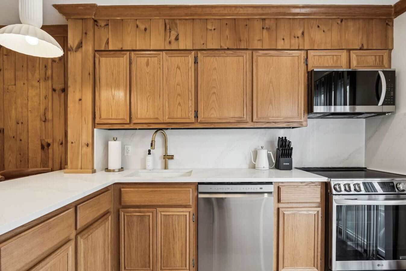 A kitchen with wooden cabinets, stainless steel appliances, and a white countertop.