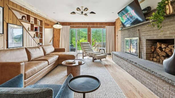 A modern living room with a fireplace, leather sofa, and a large flat-screen TV.