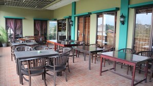 A restaurant with brick flooring, wooden tables and chairs, and large windows with curtains. - Hotel Green Wattana Sentul (Citaringgul)