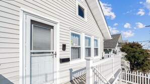 A white house with a front porch, a mailbox, and a small window. - 2 BR Ocean Block Home (Seaside Park)