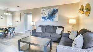 A modern living room with a grey sofa, a coffee table, and a dining area with a table and chairs. - 2 Mi to Branson Strip: Family Condo w/ Balcony! (Branson)