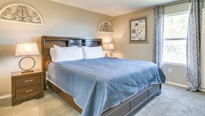 A bedroom with a bed, two bedside tables, a nightstand, a window with curtains, and wall art. - 2 Mi to Branson Strip: Family Condo w/ Balcony! (Branson)