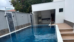 Ein rechteckiger Swimmingpool mit weißem Rand, umgeben von einer Pflasterterrasse.