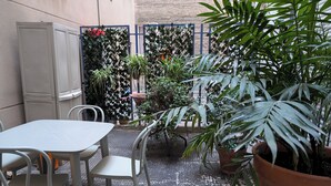 An outdoor patio with a table and chairs, surrounded by potted plants and a decorative fence. - Serendipity (Zaragoza)