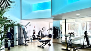 Un gimnasio moderno con diverso equipo de ejercicio, ventanas amplias y piso de madera.