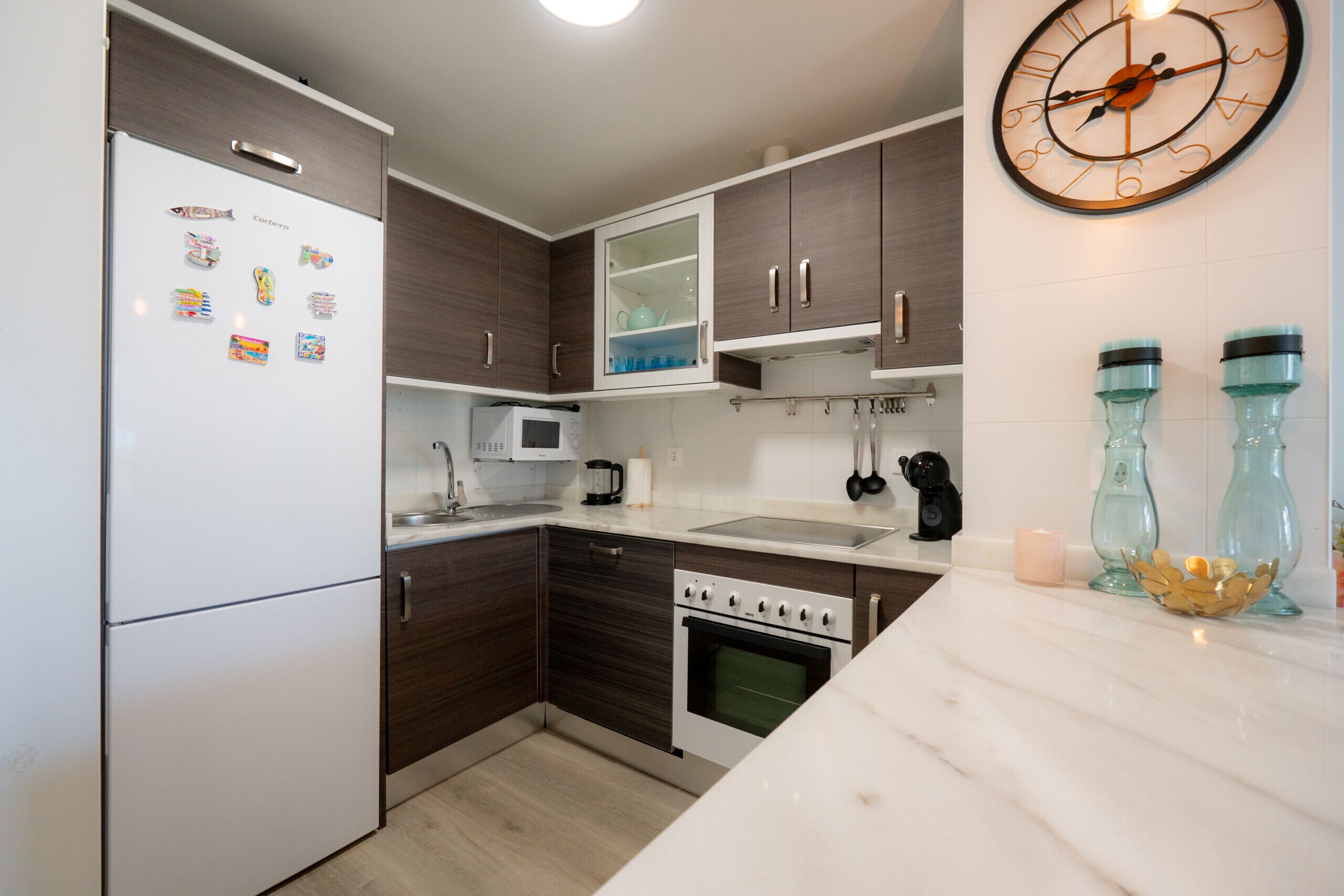 Una cocina moderna con refrigerador, horno, microondas, lavamanos y armarios.