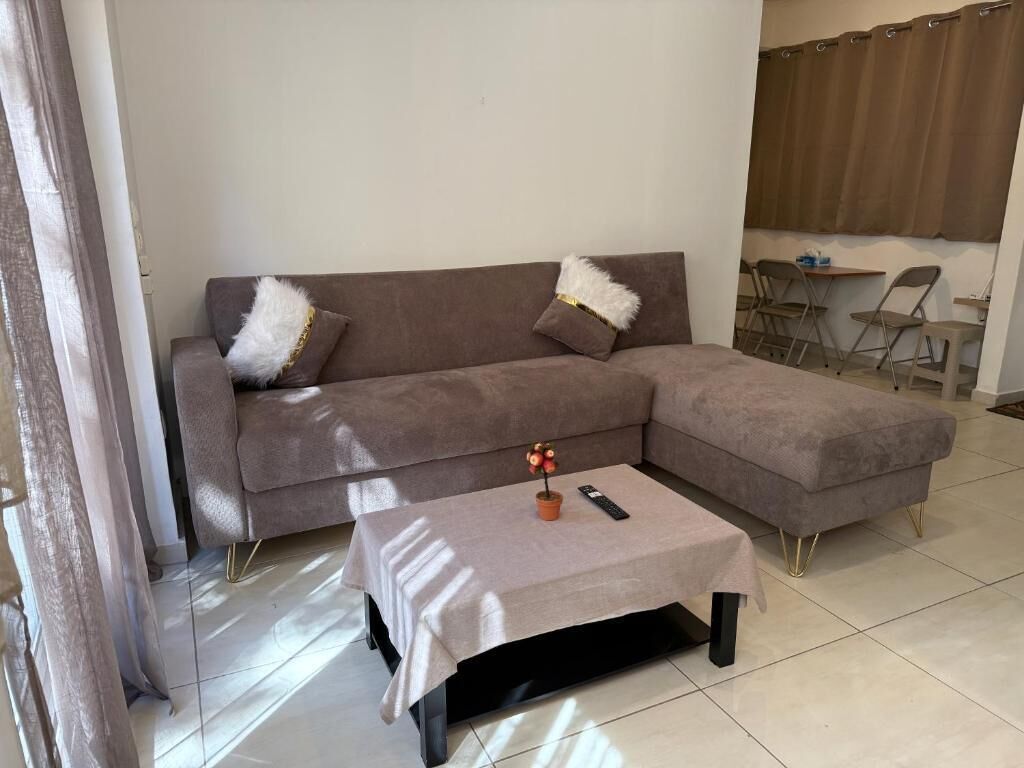 A modern living room with a grey sectional sofa, a small coffee table, and a dining area with chairs and a table.