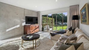 Una sala de estar con televisor, sofá y una mesa de centro.