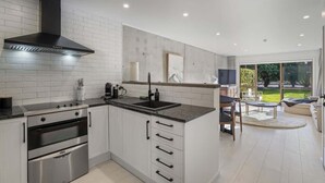Una cocina moderna con electrodomésticos de acero inoxidable, una campana extractora negra y una isla grande con un lavamanos.