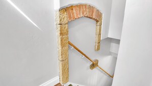Esquina de una habitación con un arco de ladrillo en construcción y una viga de madera.