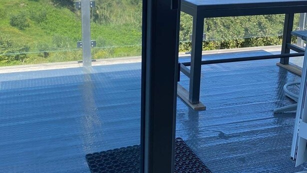A balcony with a view of the sea, a table, and a chair.