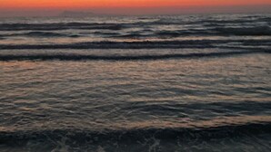 A beach with waves at sunset.