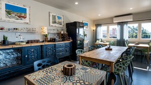 A dining area with a wooden table and chairs, a patterned tile floor, and a bar area with glassware and a lamp. - Villa's Pomar do Moinho - 5min de Óbidos (Obidos)