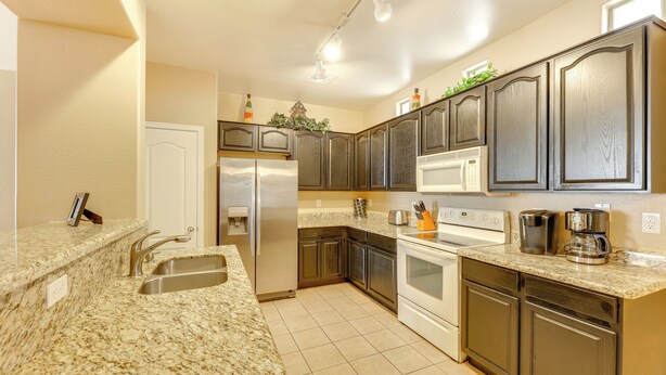 A kitchen with granite countertops, stainless steel appliances, and dark wooden cabinets. - Family Home w/ Community Perks - 8 Mi to Chandler! (Gilbert)