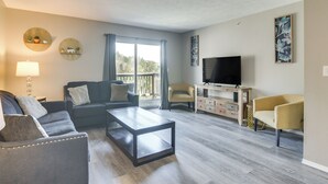 Un salon moderne avec un canapé, une table basse, un téléviseur et des œuvres d’art accrochées aux murs.