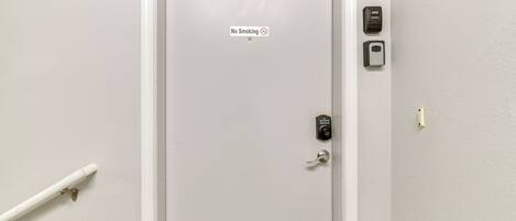 A door with a "No Smoking" sign, a keypad lock, and a door handle.