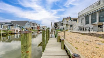A wooden pier leading to a dock with boats, surrounded by residential buildings with balconies and outdoor seating areas.