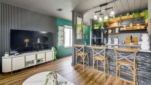 Eine moderne Küche mit Barbereich, Holzboden und einem gro ßen Fernseher.