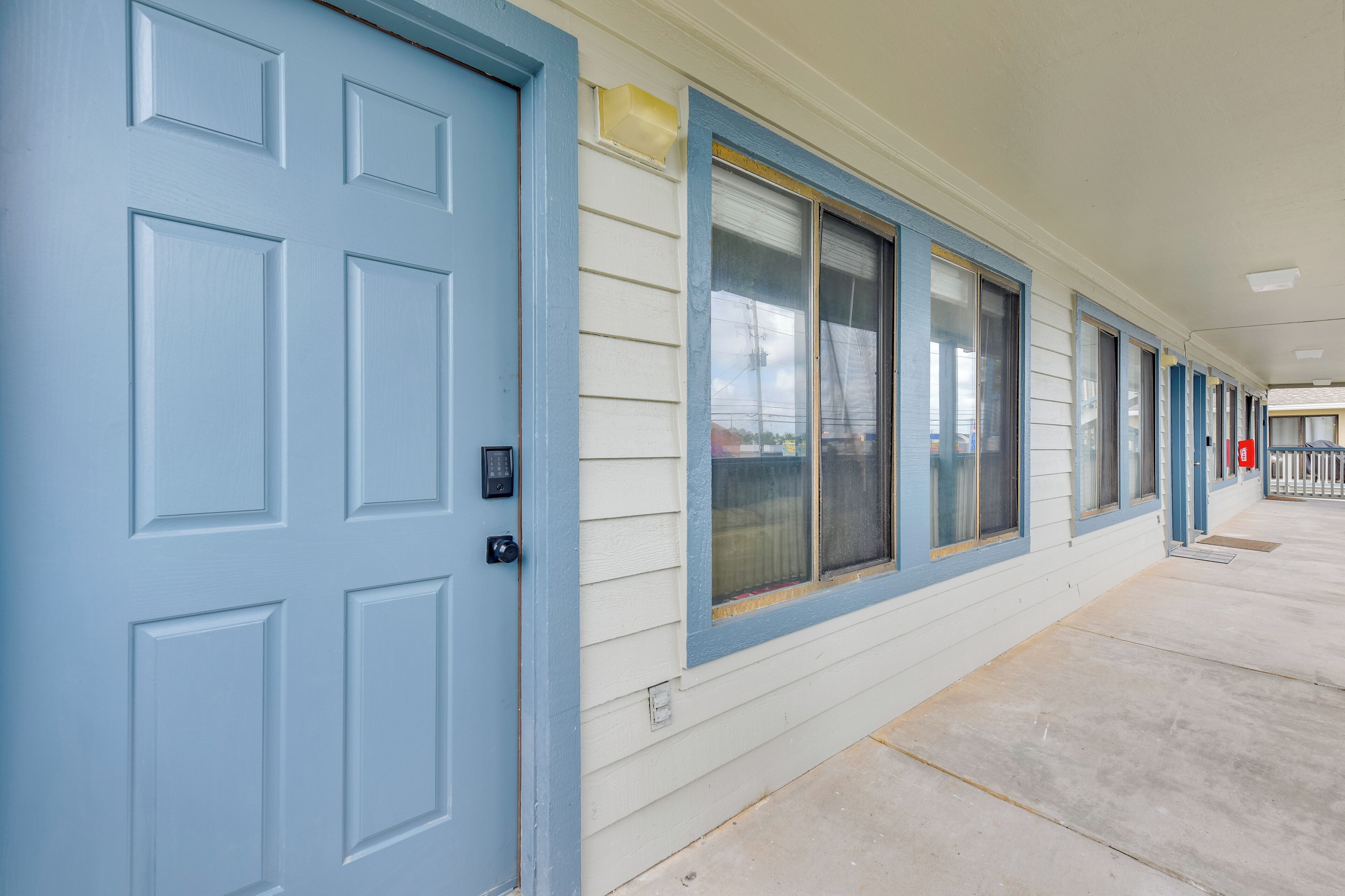 A building with a blue door and windows, a covered walkway, and a fire extinguisher.