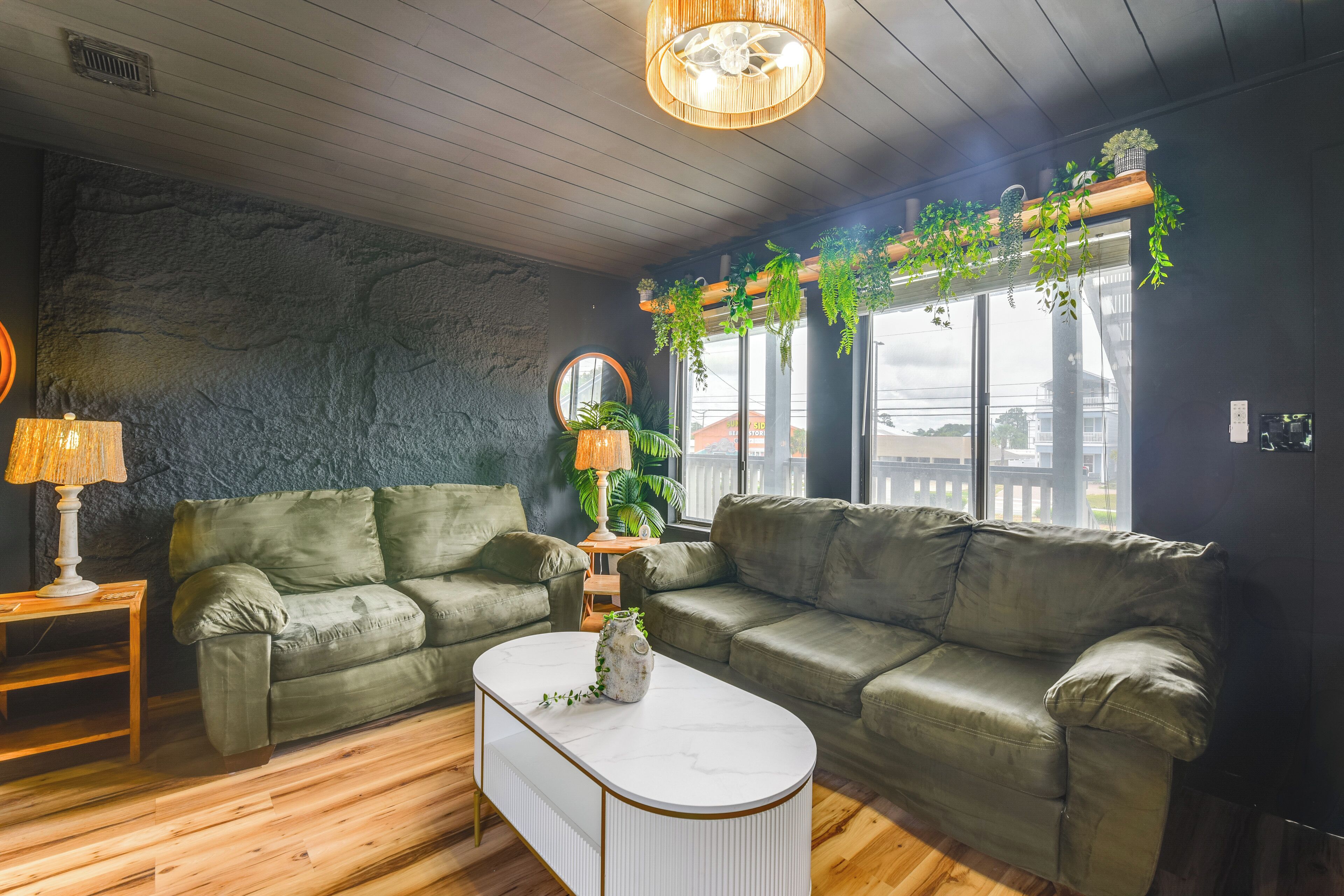 A modern living room with two green sofas, a white coffee table, and a wooden floor.