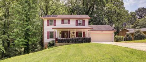 A two-story house with a front porch, a garage, and a well-maintained lawn.