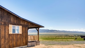 A rustic wooden building with a porch, a fenced field, and mountains in the background. - 2 Mi to Big Hole River: Mtn-view Montana Haven (Twin Bridges)