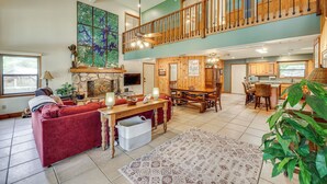 A spacious living area with a red sofa, wooden dining table, and a large rug. - Waterfront Gem on Lake Martin w/ Kayaks & Dock! (Eclectic)