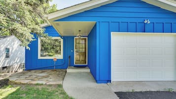 Uma casa com fachada azul, porta de garagem branca e calçada de pedra.