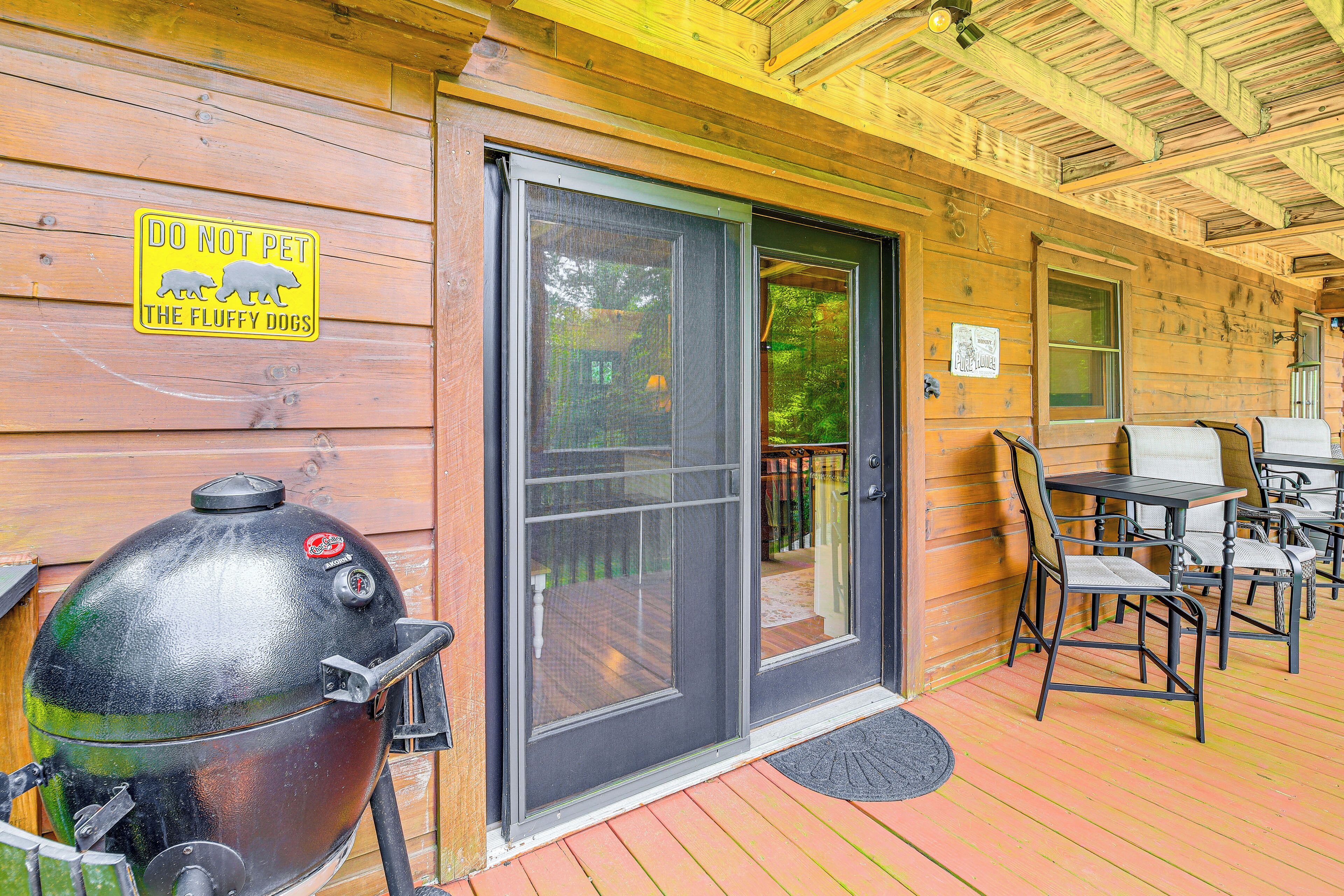 A wooden cabin with a sliding glass door, a barbecue grill, and outdoor seating.