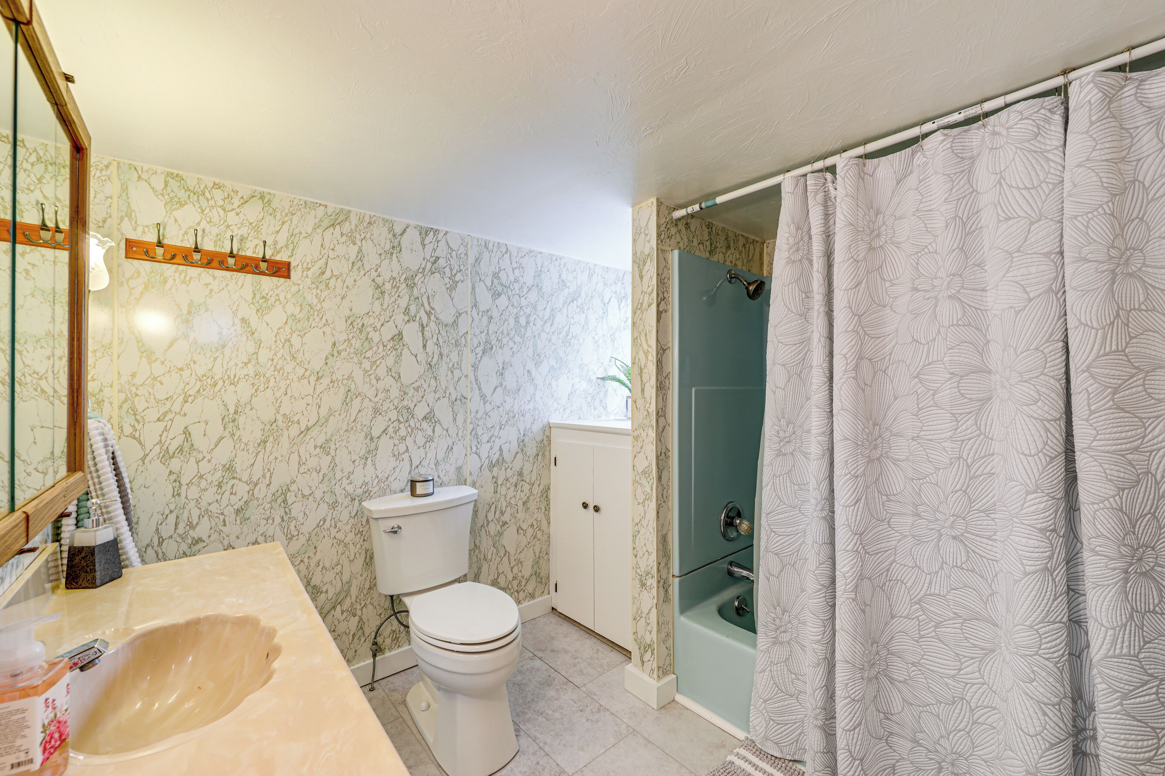 A bathroom with a marble wall, a toilet, a sink, and a shower area.