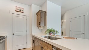 A modern kitchen with white cabinetry, a stainless steel sink, and a wooden countertop. - 5 Mi to Trails: Townhome in Eagle Mountain (Eagle Mountain)