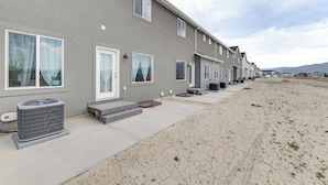 A row of modern townhouses with large windows, a concrete pathway, and a dry, cracked ground. - 5 Mi to Trails: Townhome in Eagle Mountain (Eagle Mountain)