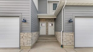 A two-story building with a garage entrance, stone steps, and two garage doors. - 5 Mi to Trails: Townhome in Eagle Mountain (Eagle Mountain)