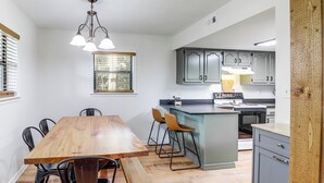 A modern kitchen with a wooden dining table, bar stools, and a built-in island.