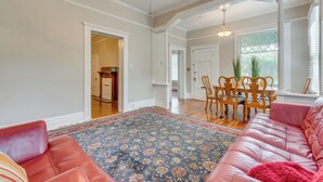A spacious living room with a large, patterned rug, a leather sofa, and a dining area with a wooden table and chairs.
