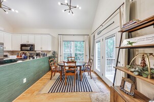 A kitchen with white cabinets, a wooden dining table, and a striped rug.