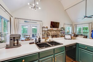 A kitchen with a coffee maker, sink, and green cabinets.