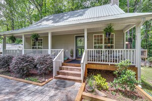 A two-story house with a porch, wooden steps, and a garden area with various plants.