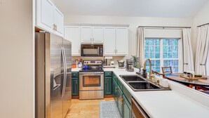 A modern kitchen with stainless steel appliances, white cabinets, and a large window with curtains. - Fisher's Retreat Near Lake Thurmond: Tignall Home (Tignall)