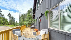 Um terraço com móveis para área externa, uma banheira de hidromassagem e vista para uma área arborizada.