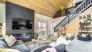 Uma sala de estar moderna com sofá, mesa de centro e escada que leva a um espaço de bar.