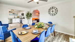 A dining area with a wooden table, blue chairs, a clock, and a ceiling fan. - Newly Renovated Albuquerque Retreat w/ Pool Table (Albuquerque)