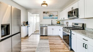 A modern kitchen with stainless steel appliances, white cabinetry, and a granite countertop. - Newly Renovated Albuquerque Retreat w/ Pool Table (Albuquerque)