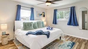 A bedroom with a bed, a ceiling fan, a window with curtains, and a nightstand with a lamp. - Newly Renovated Albuquerque Retreat w/ Pool Table (Albuquerque)