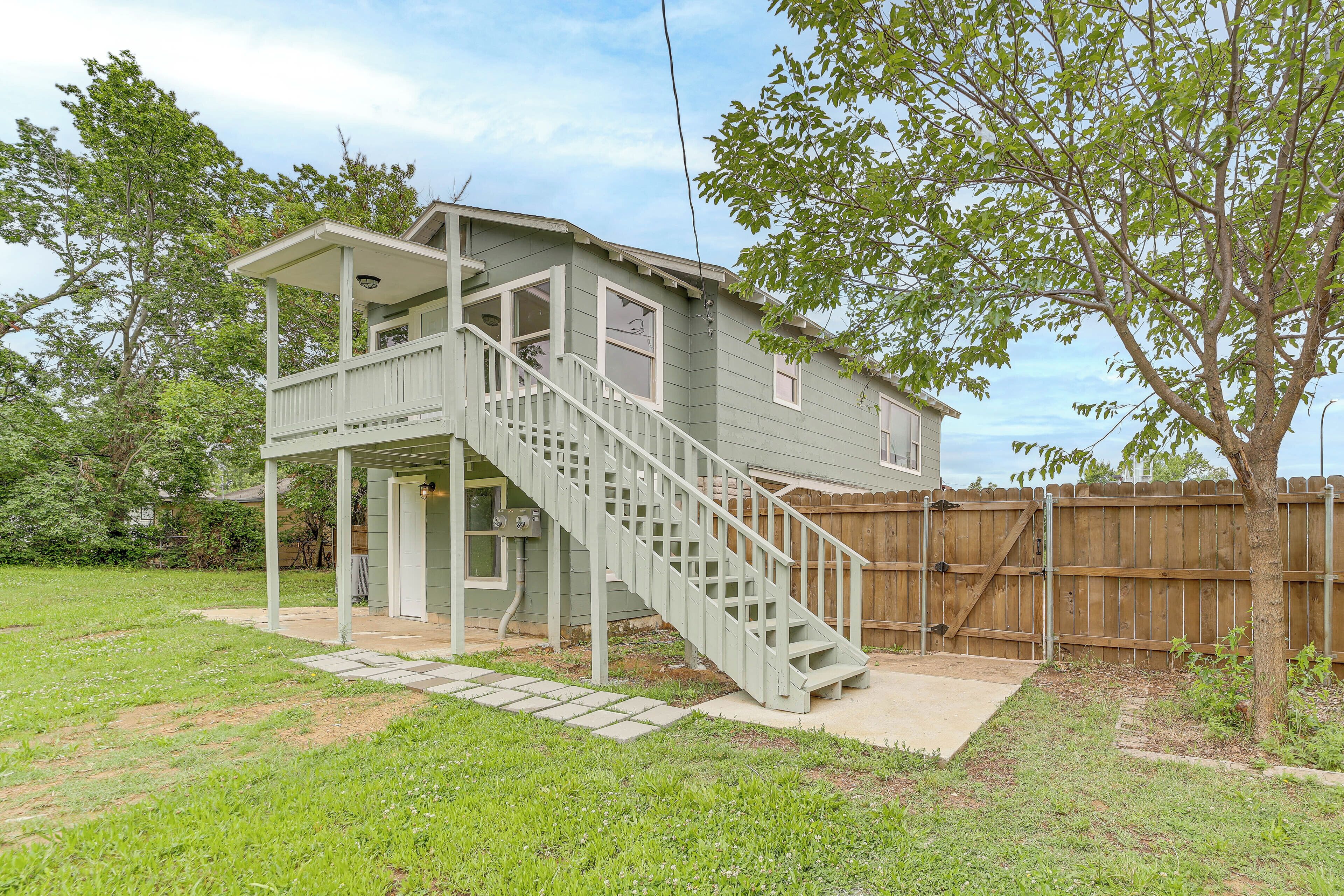 A two-story house with a covered porch and a staircase leading to the upper level.