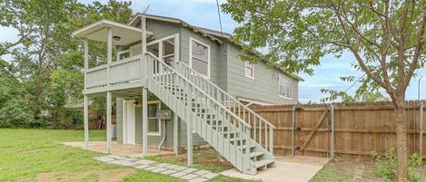 A two-story house with a covered porch and a staircase leading to the upper level.